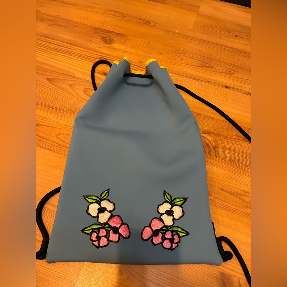 Triangl blue neoprene drawstring wet bikini backpack with floral patches.